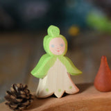 An Ostheimer hand made and hand painted wooden snowdrop Flower Child figure toy placed on a natural Grimm's celebration ring. These flower child wooden figures are part of a wide range of expertly hand crafted wooden toys here at Babipur. 