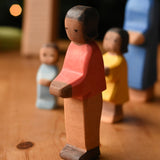 An Ostheimer son wooden toy figure with brown skin placed at the front of a small world play scene. These wooden figures are part of a wide range of expertly hand crafted wooden toys here at Babipur.