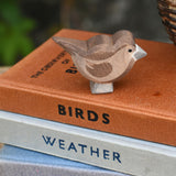 An Ostheimer brown sparrow bird figure placed on a top of a pile of books.