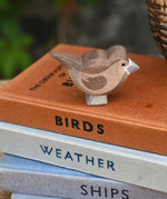 An Ostheimer brown sparrow bird figure placed on a top of a pile of books.