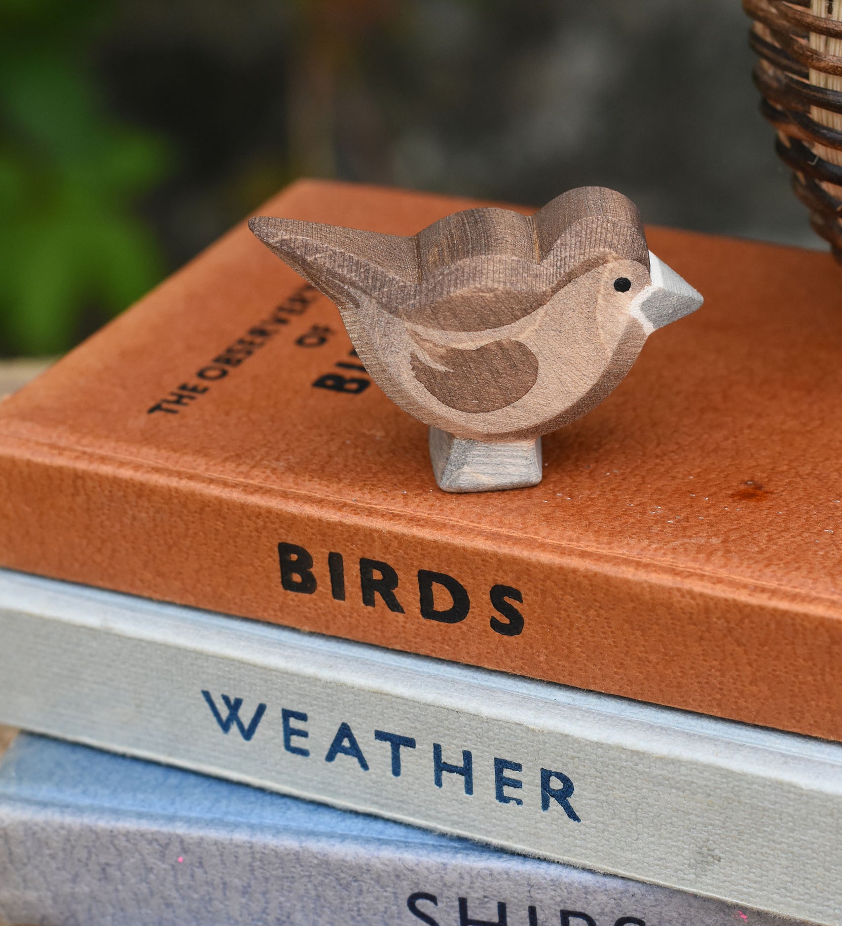 An Ostheimer brown sparrow bird figure placed on a top of a pile of books.