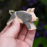 Ostheimer spotted piglet wooden toy animal figure in an adult's hand.
