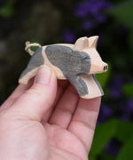Ostheimer spotted piglet wooden toy animal figure in an adult's hand.