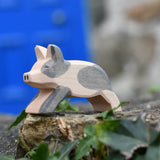 Ostheimer spotted piglet wooden toy animal figure placed on a stone wall outdoors