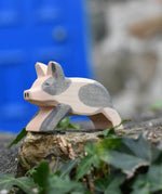 Ostheimer spotted piglet wooden toy animal figure placed on a stone wall outdoors