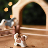An Ostheimer small St Bernard dog wooden toy figure placed on a wooden surface. These wooden figures are part of a wide range of expertly hand crafted wooden toys here at Babipur. 