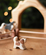 An Ostheimer small St Bernard dog wooden toy figure placed on a wooden surface. These wooden figures are part of a wide range of expertly hand crafted wooden toys here at Babipur. 
