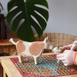 Child playing with Ostheimer brown standing cow figure placing a calf in front of it. 