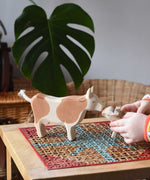 Child playing with Ostheimer brown standing cow figure placing a calf in front of it. 