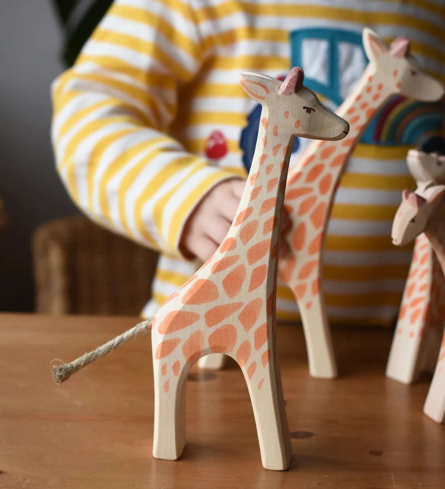 Ostheimer standing giraffe wooden toy figure placed on a wooden surface with other giraffes in the background. 