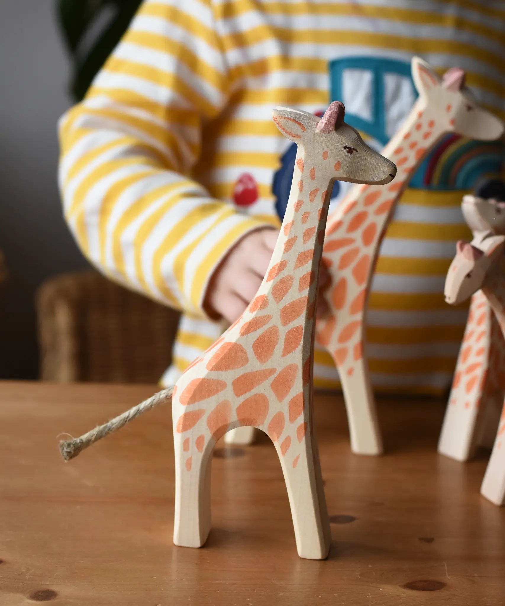 Ostheimer standing giraffe wooden toy figure placed on a wooden surface with other giraffes in the background. 