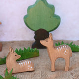 Ostheimer sitting and standing deer fawn wooden figures placed in a small world play scene with other wooden Ostheimer figure including wooden green grass and an oak tree.
