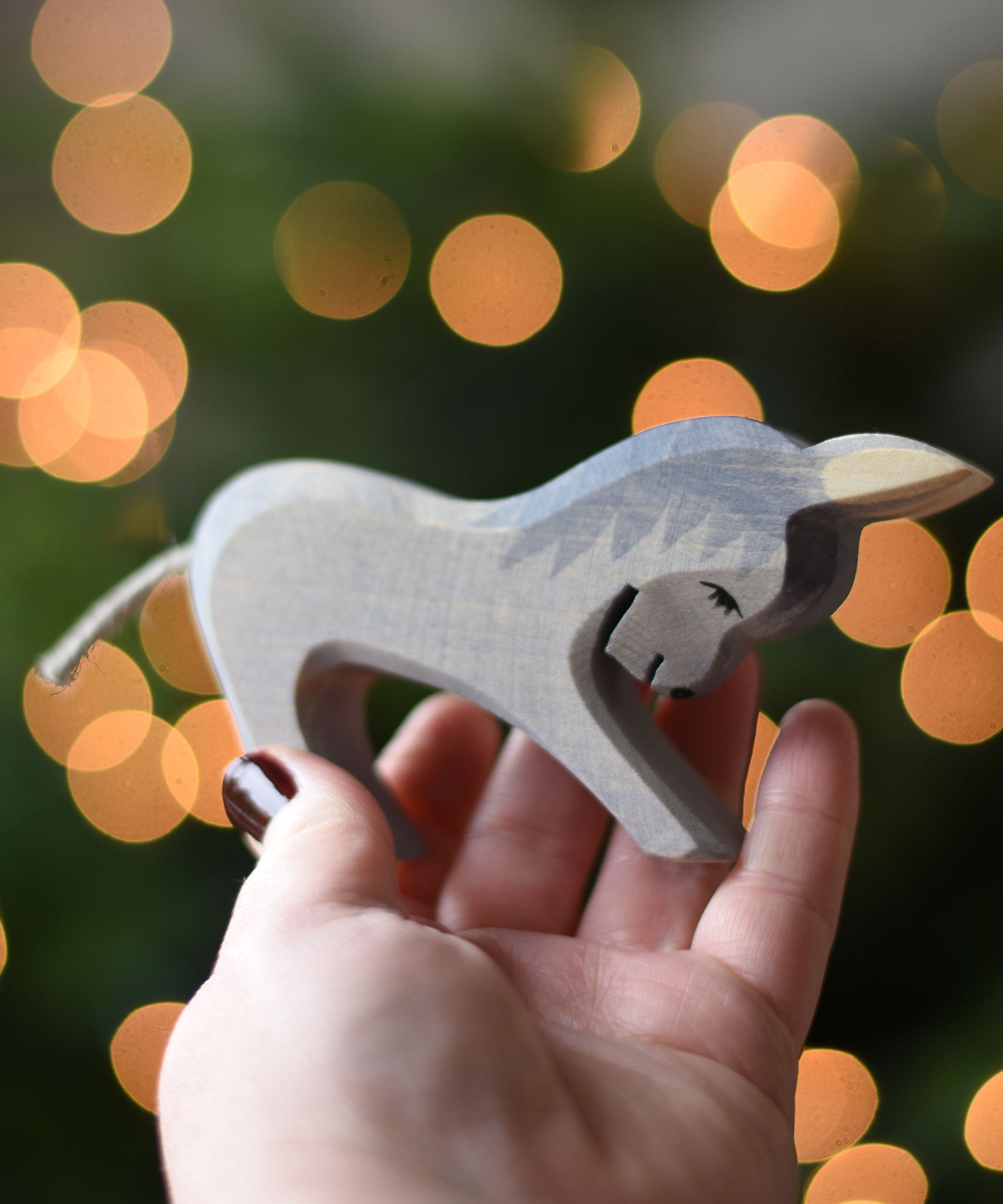 An Ostheimer stubborn donkey wooden toy figure in an adult's hand. Ostheimer's range of hand crafted, heirloom quality wooden toys are available to buy at Babipur. 