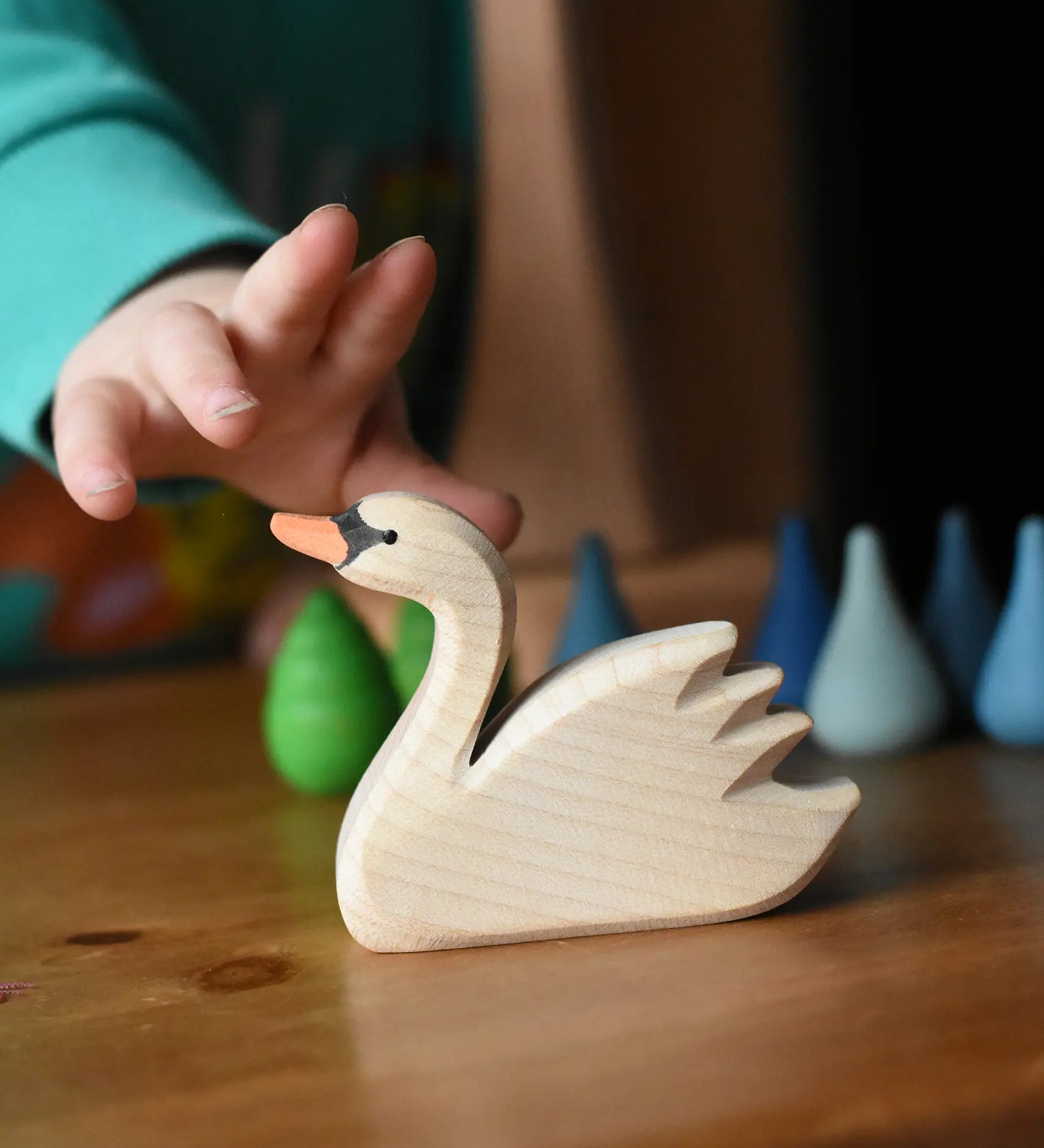 Ostheimer swan with high head placed on a wooden surface with Grapat mandala pieces in the background.