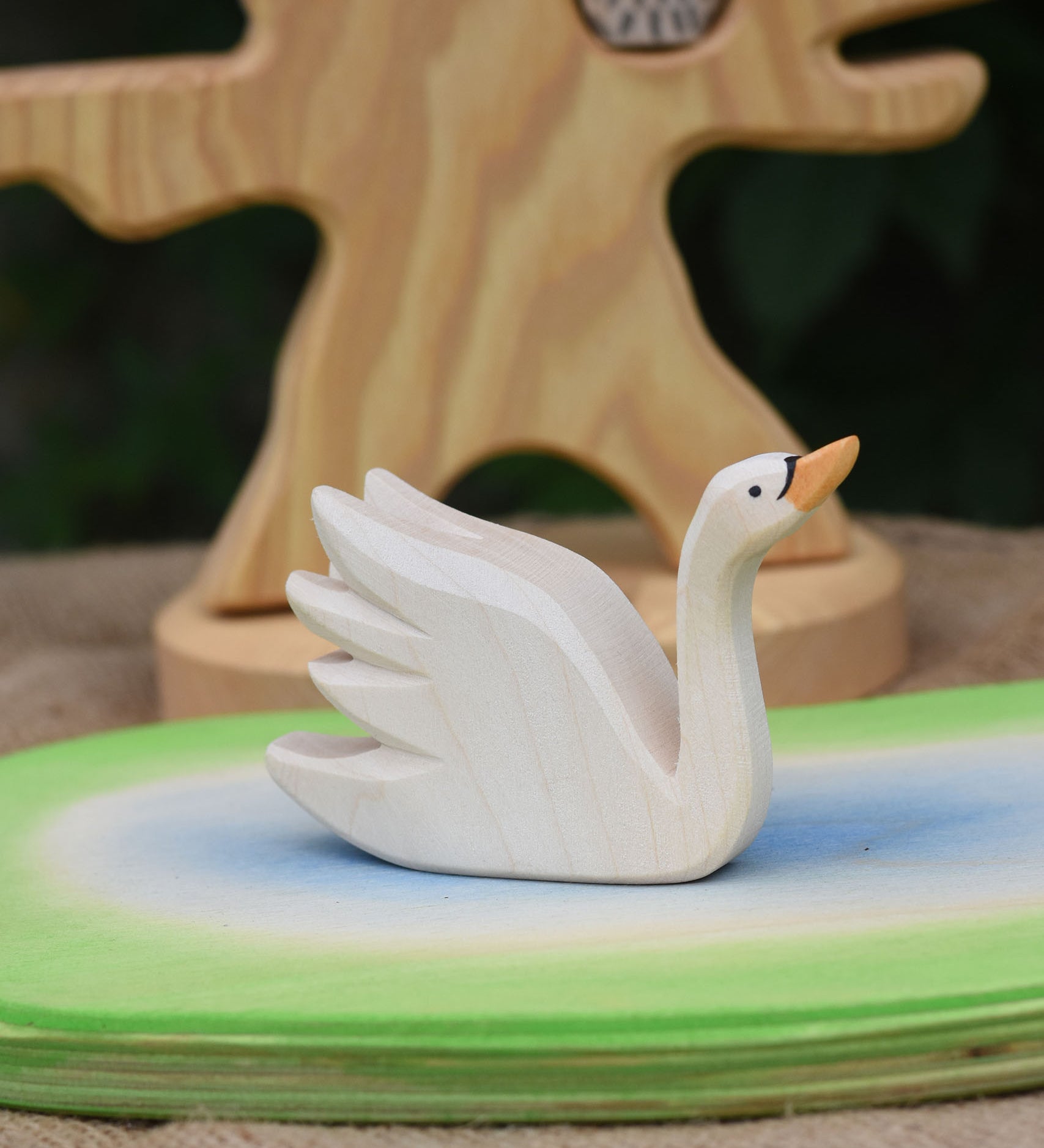 An Ostheimer Swan with High Neck wooden toy figure placed on a wooden pond scene piece.