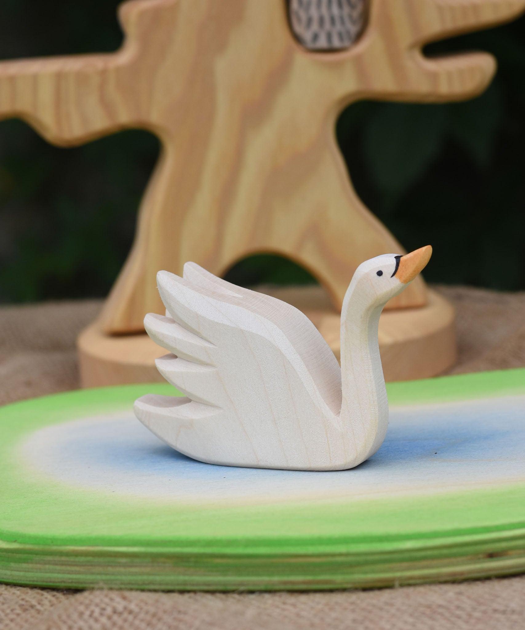 An Ostheimer Swan with High Neck wooden toy figure placed on a wooden pond scene piece.