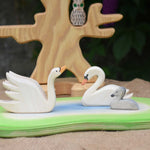 Two Ostheimer swans and a cygnet placed on a pond scene piece in a small world play set up with the bird tree in the background. 