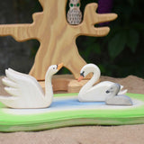 Two Ostheimer swans and a cygnet placed on a pond scene piece in a small world play set up with the bird tree in the background. 