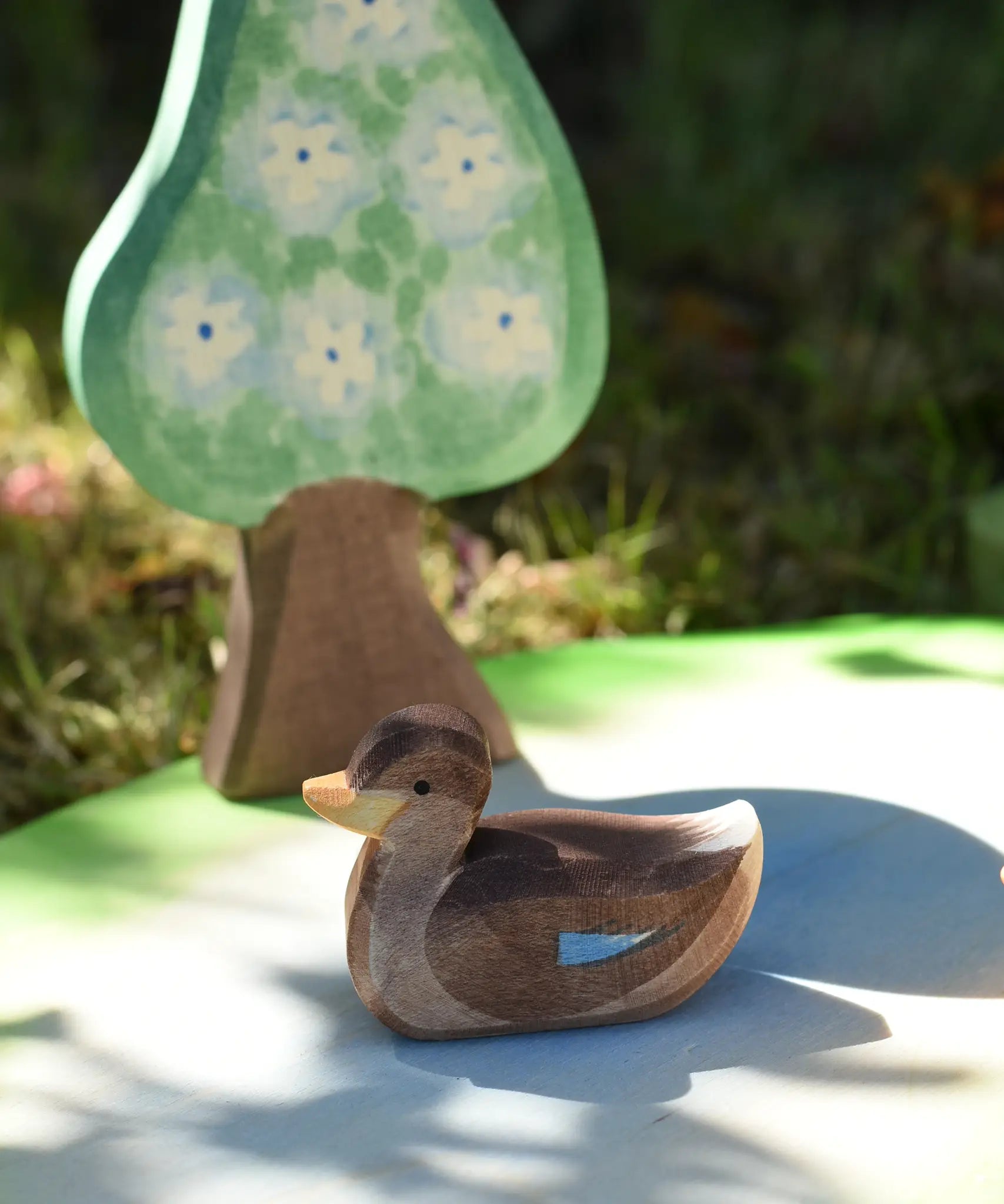 Ostheimer swimming duck placed on a pond piece with a pear tree in the background.