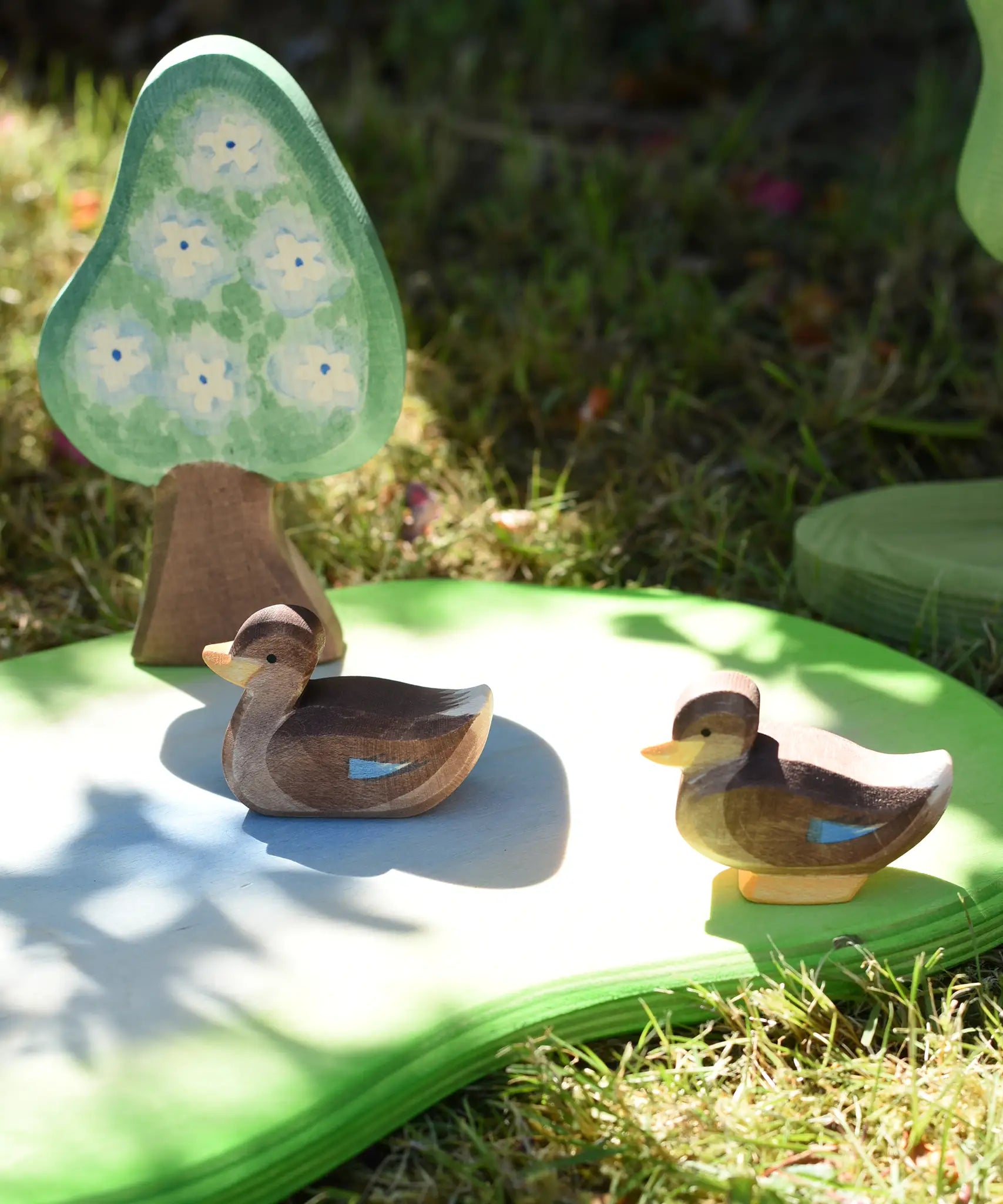 Ostheimer swimming and sitting ducks wooden toy figures placed on a pond piece.