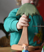 Child holding an Ostheimer tall palm tree in their hands.