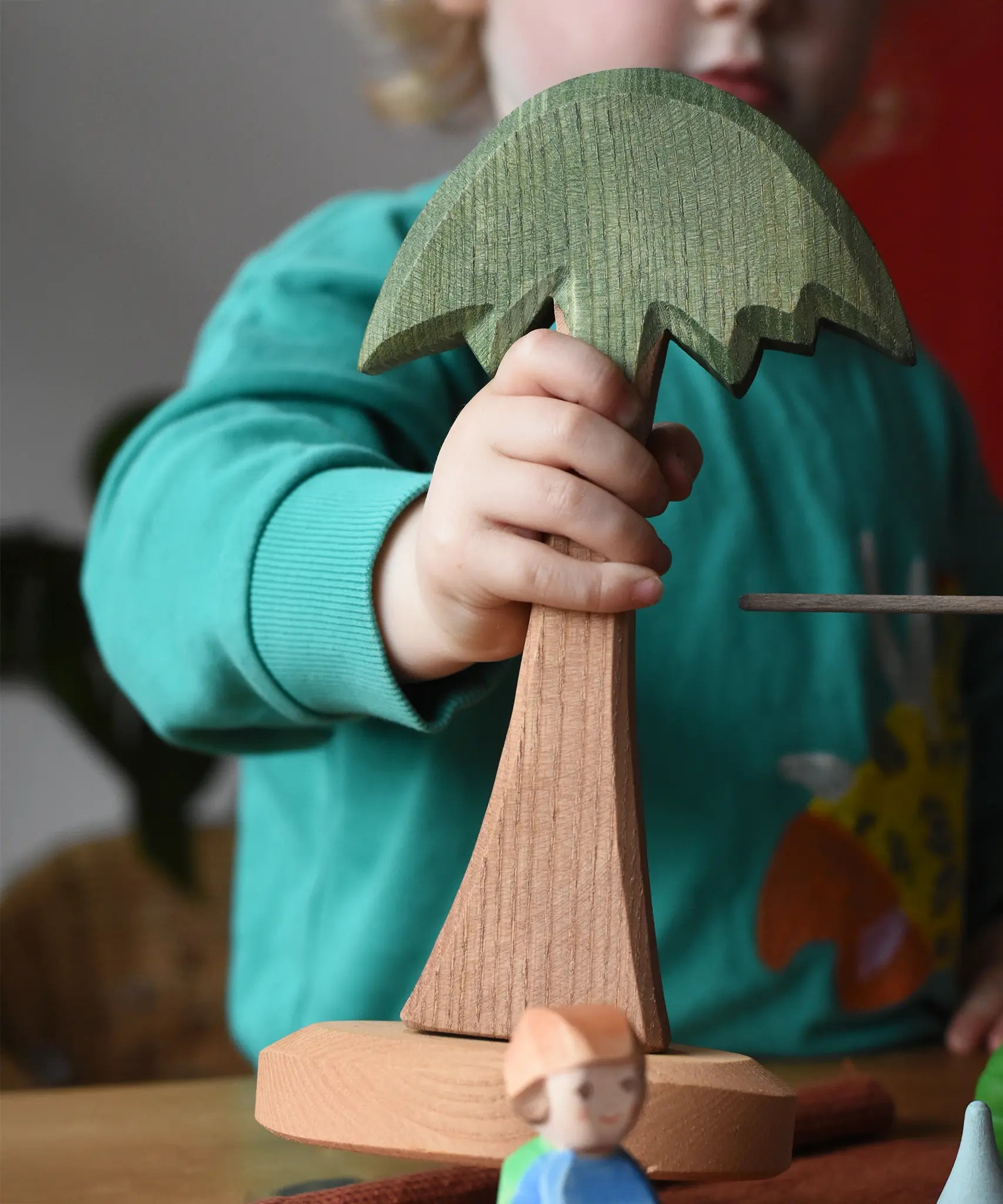 Child holding an Ostheimer tall palm tree in their hands.