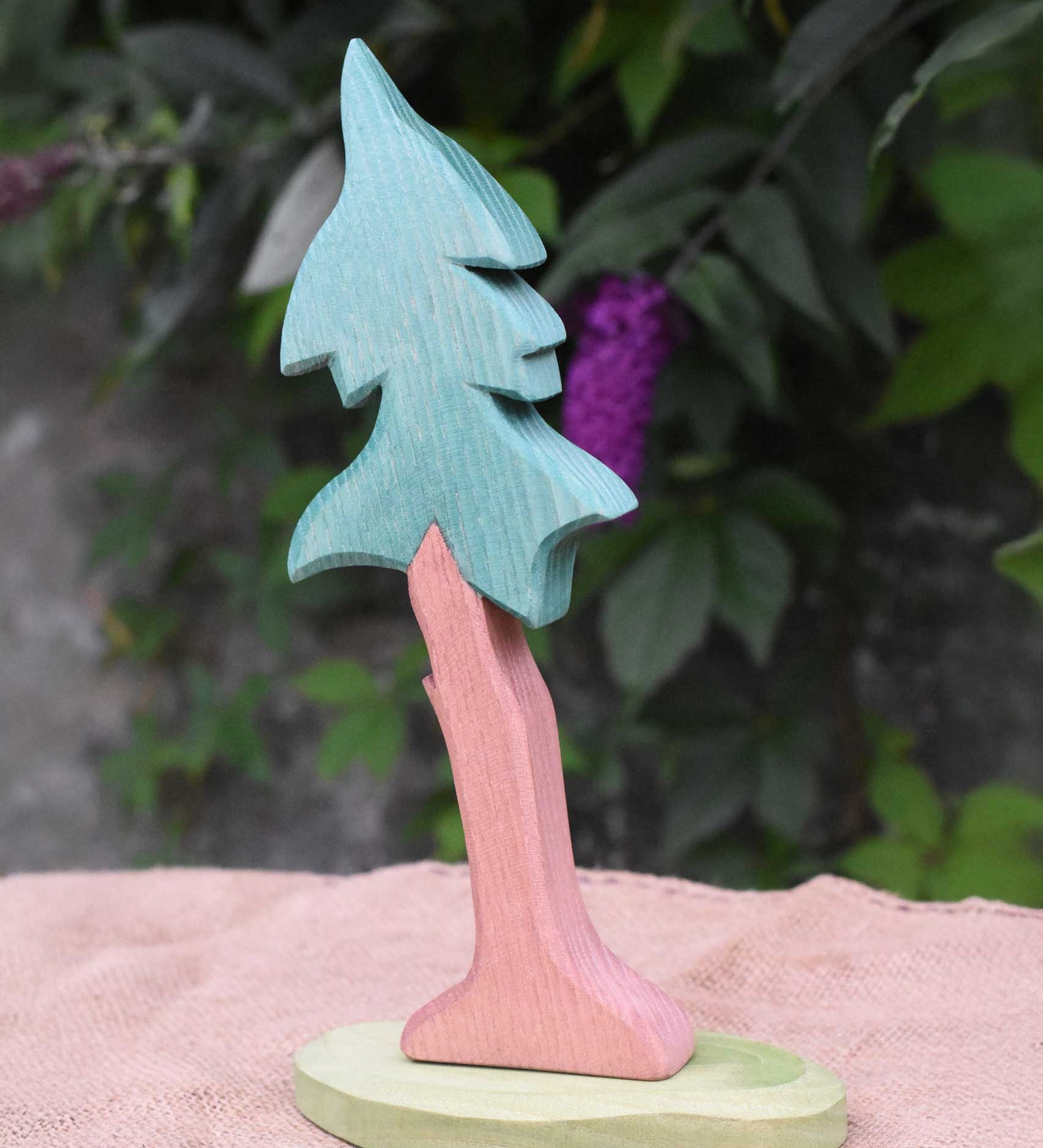 A tall Ostheimer spruce tree with support placed on a jute covered surface. 