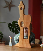 Ostheimer tower with stairs wooden toy building with a child standing  large behind and peering through the window.