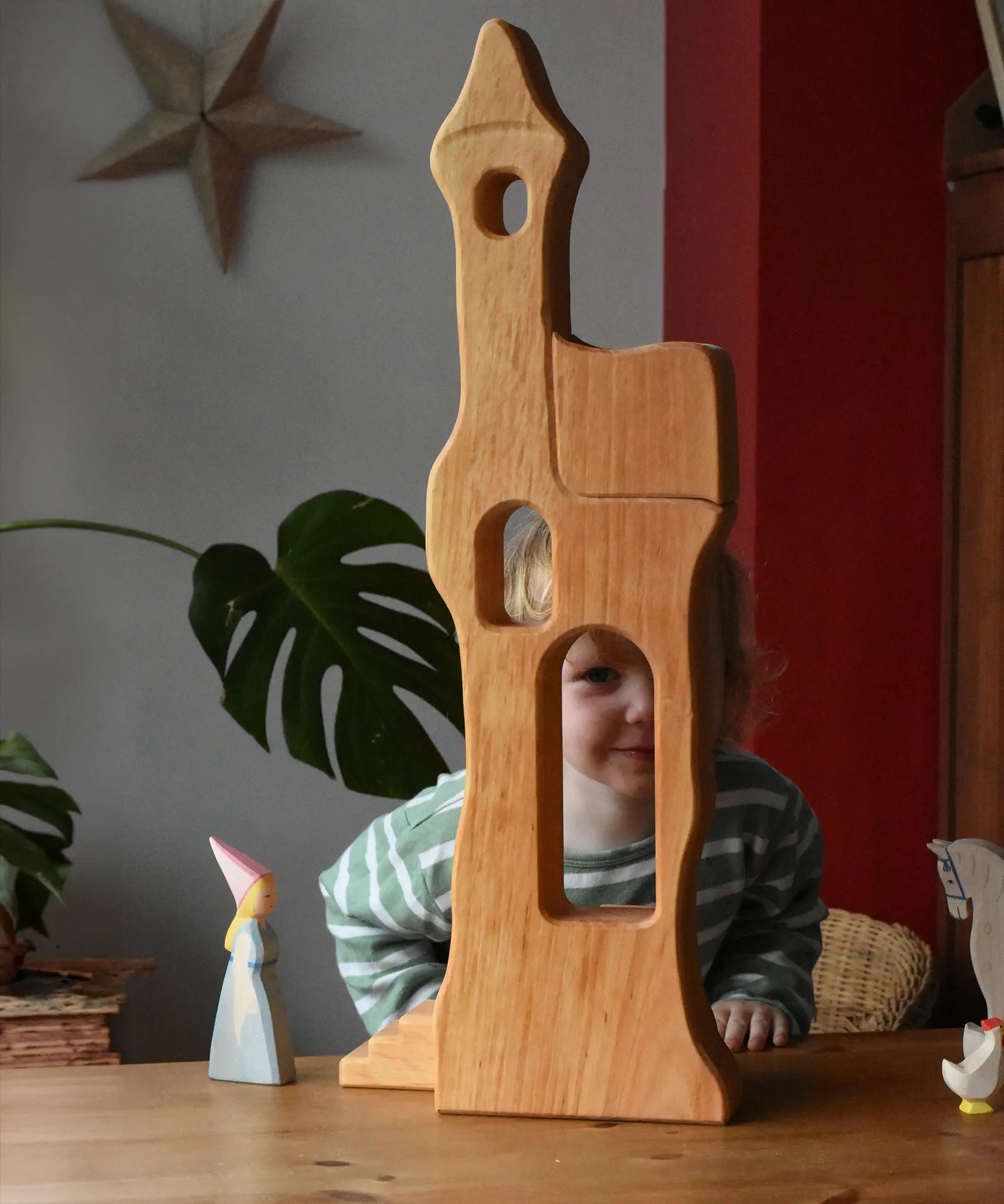 Ostheimer tower with stairs wooden toy building with a child standing  large behind and peering through the window.