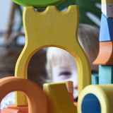 A child peering through the yellow castle shaped piece from the Ostheimer Rainbow Castle Block set. 