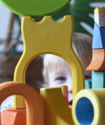 A child peering through the yellow castle shaped piece from the Ostheimer Rainbow Castle Block set. 