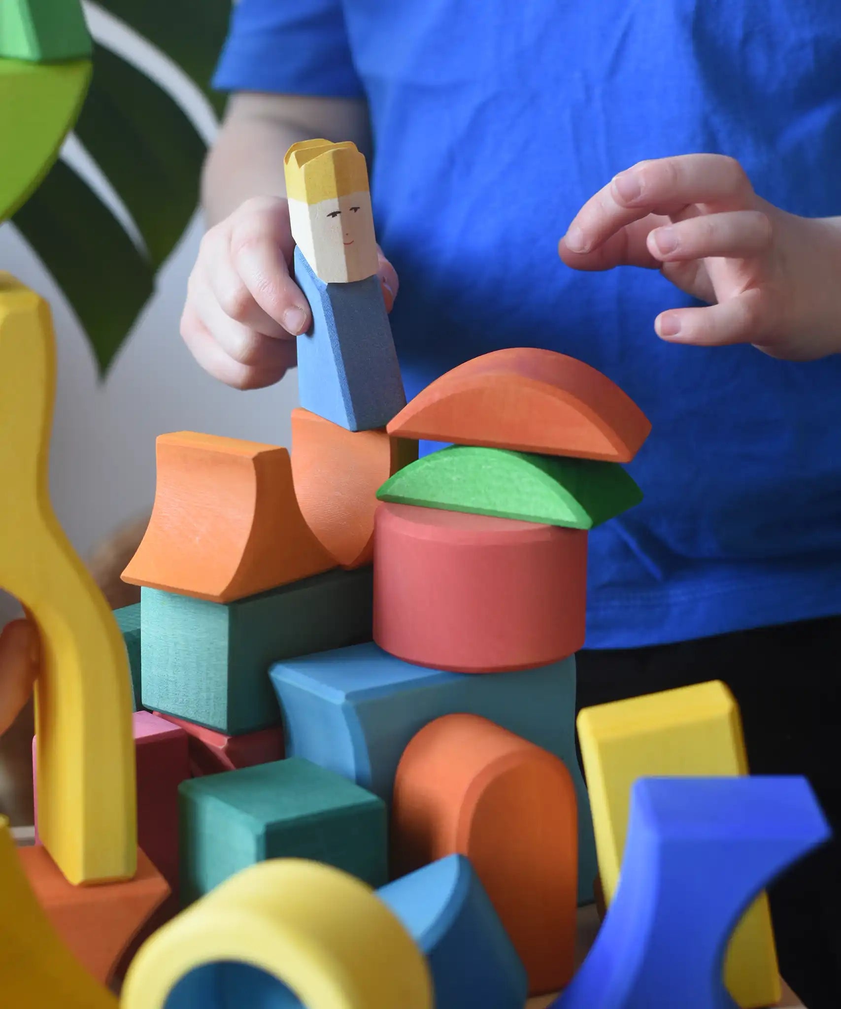 Ostheimer Rainbow Castle Block set played with by a child placing a blue king wooden figure on the blocks.