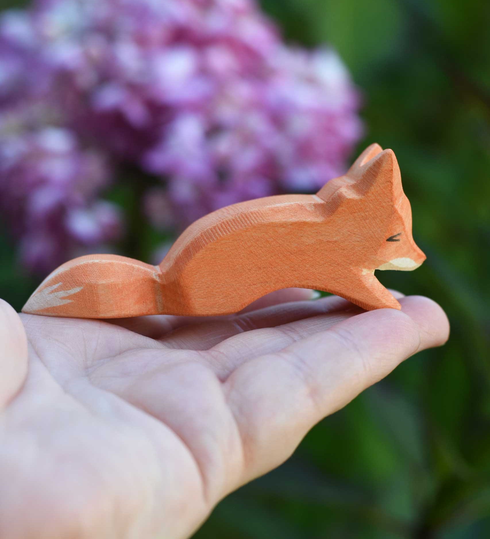 An Ostheimer Small Creeping Fox wooden toy figure shown in an adult's hand for scale. 