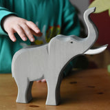 Child's hand reaching for the Ostheimer trumpeting bull elephant wooden toy figure. 