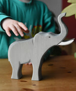 Child's hand reaching for the Ostheimer trumpeting bull elephant wooden toy figure. 