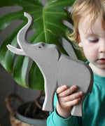 Child holding the Ostheimer trumpeting bull elephant wooden toy figure in their hand. 