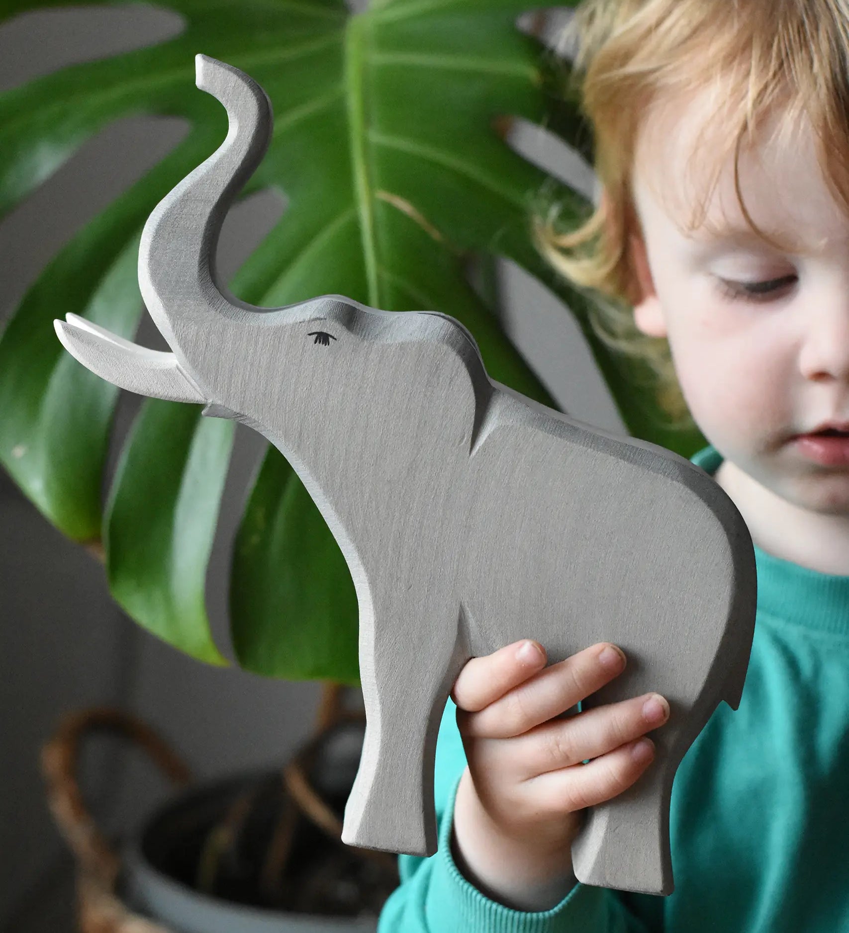 Child holding the Ostheimer trumpeting bull elephant wooden toy figure in their hand. 