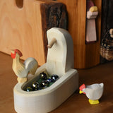 Ostheimer village well wooden toy scenery piece filled with Billes marbles with an ochre rooster placed on the side and a white hen besides it. 