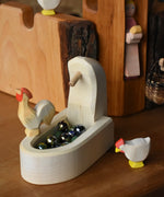 Ostheimer village well wooden toy scenery piece filled with Billes marbles with an ochre rooster placed on the side and a white hen besides it. 