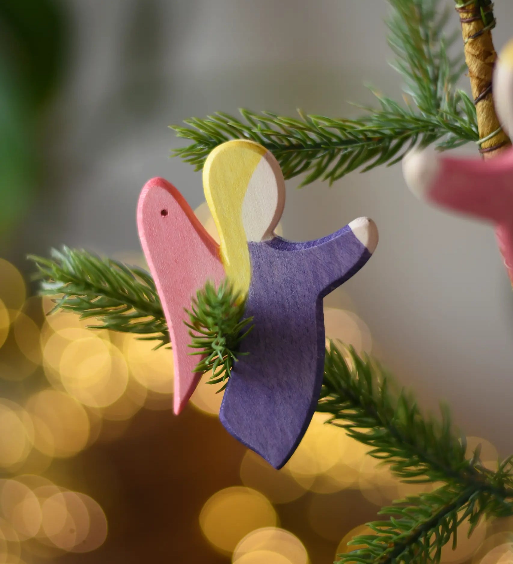 Ostheimer violet angel wooden handmade decoration placed on a Christmas tree branch. 