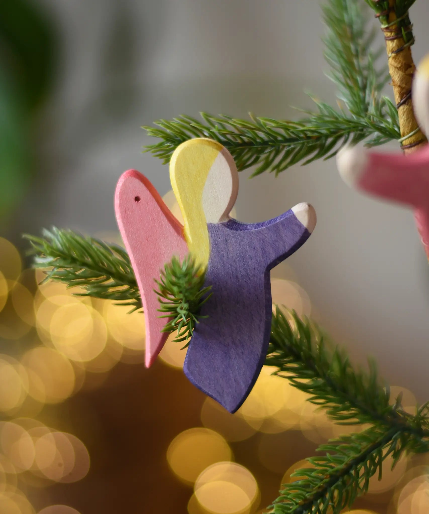 Ostheimer violet angel wooden handmade decoration placed on a Christmas tree branch. 