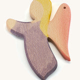 A wooden violet angel figure on a cream background