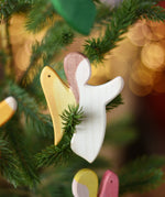 Ostheimer white angel wooden handmade decoration placed on a Christmas tree branch. 