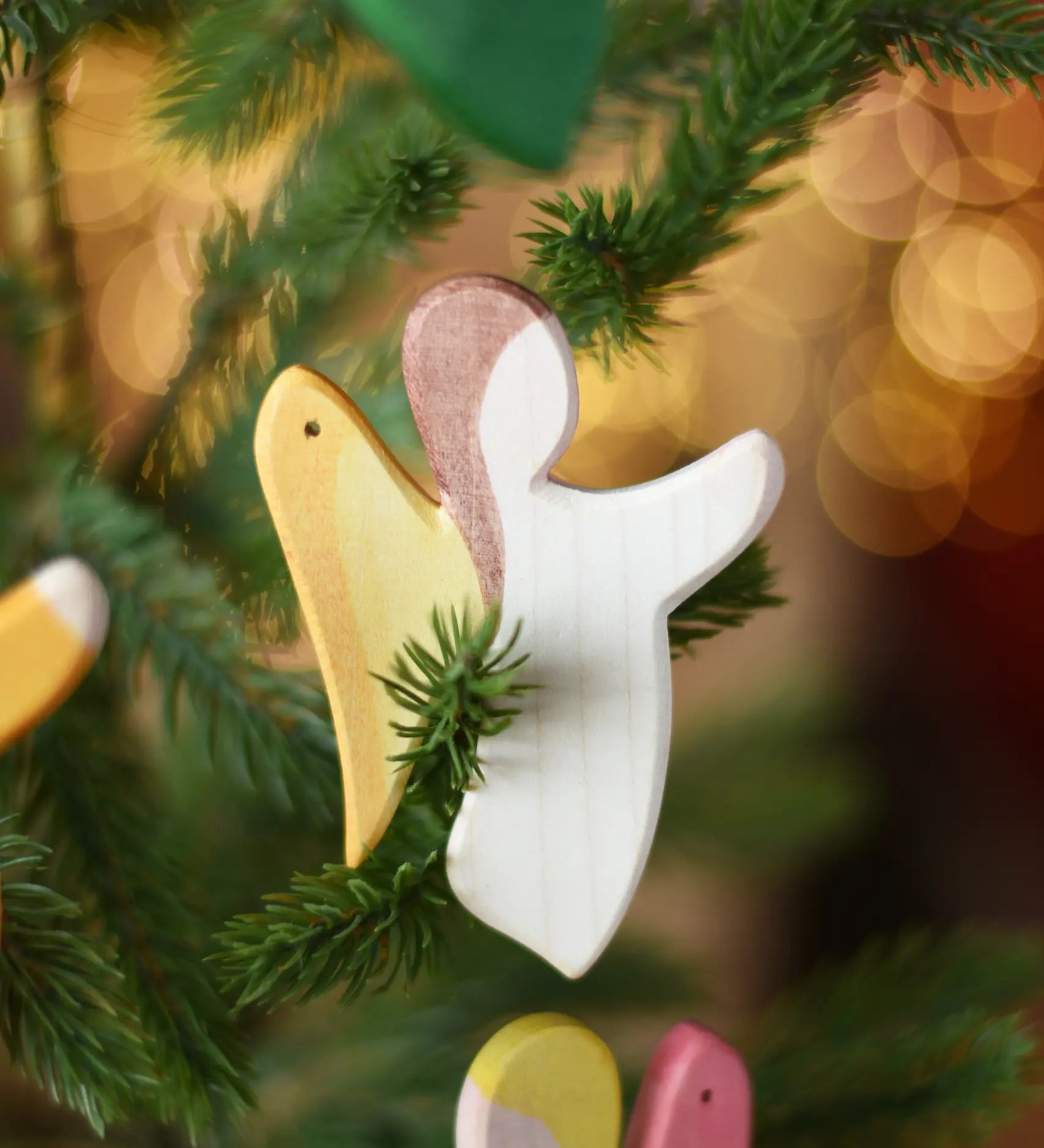 Ostheimer white angel wooden handmade decoration placed on a Christmas tree branch. 