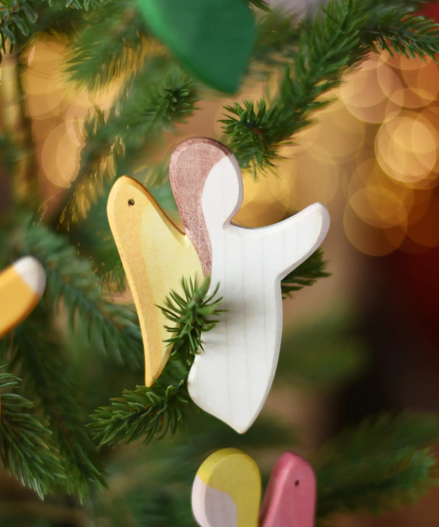 Ostheimer white angel wooden handmade decoration placed on a Christmas tree branch. 