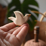 Ostheimer white dove wooden bird figure held up on an adult's fingertips.