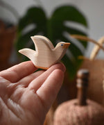 Ostheimer white dove wooden bird figure held up on an adult's fingertips.