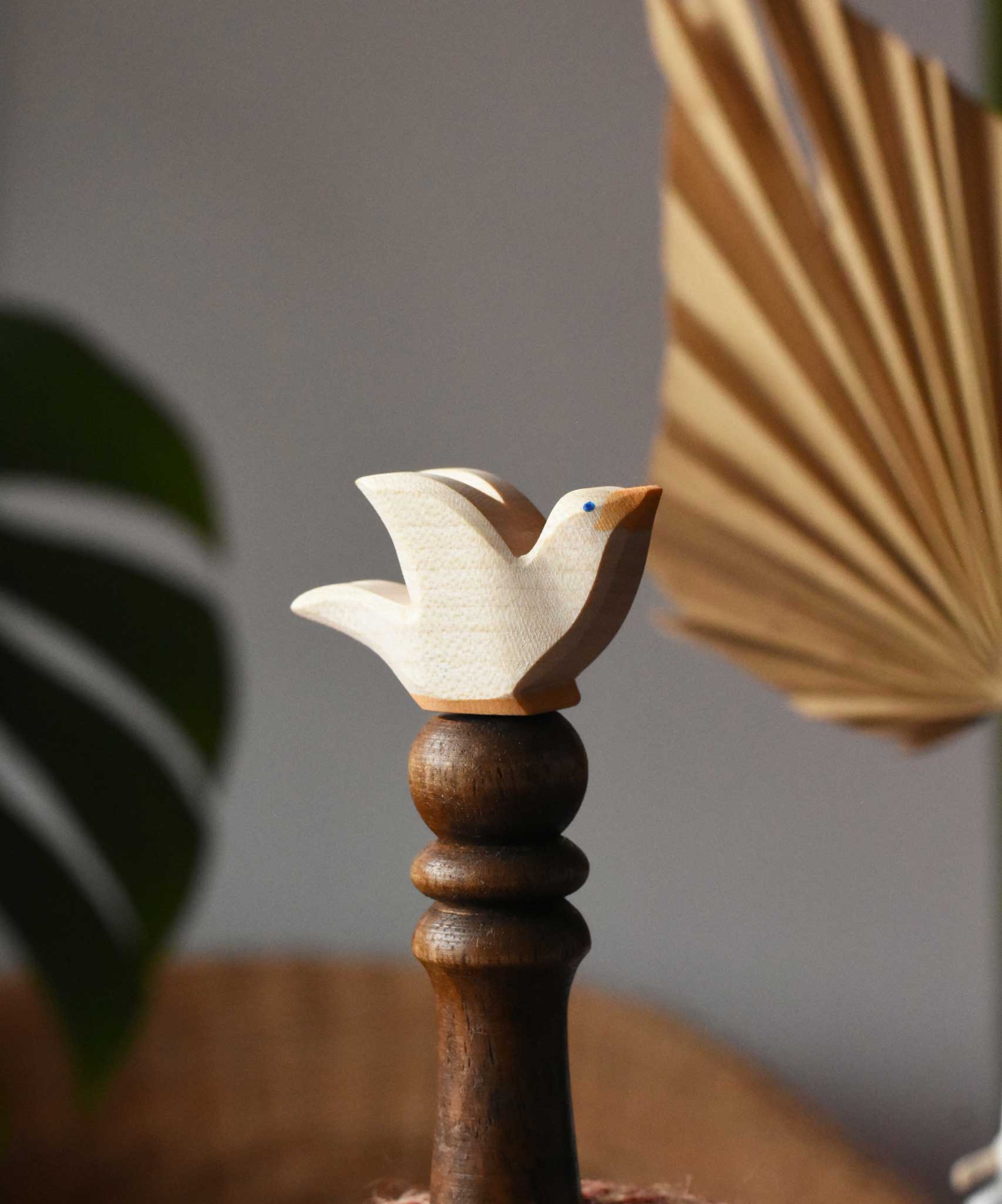 Ostheimer white dove wooden bird figure placed on a wooden stick. 