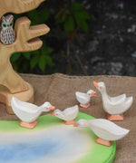 A gaggle of Ostheimer geese placed on and around the wooden pond scene piece/ The bird tree with an owl on the branch can be seen in the background.