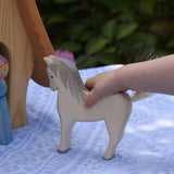 A child's hand holding the Ostheimer white horse. These wooden figures are part of a large range of expertly hand crafted, Waldorf inspired, wooden toys here at Babipur. 
